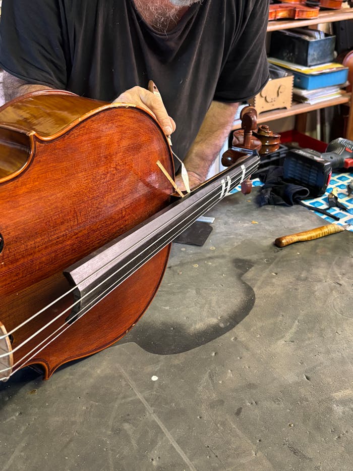A skilled craftsman meticulously restores a violin in a workshop setting.